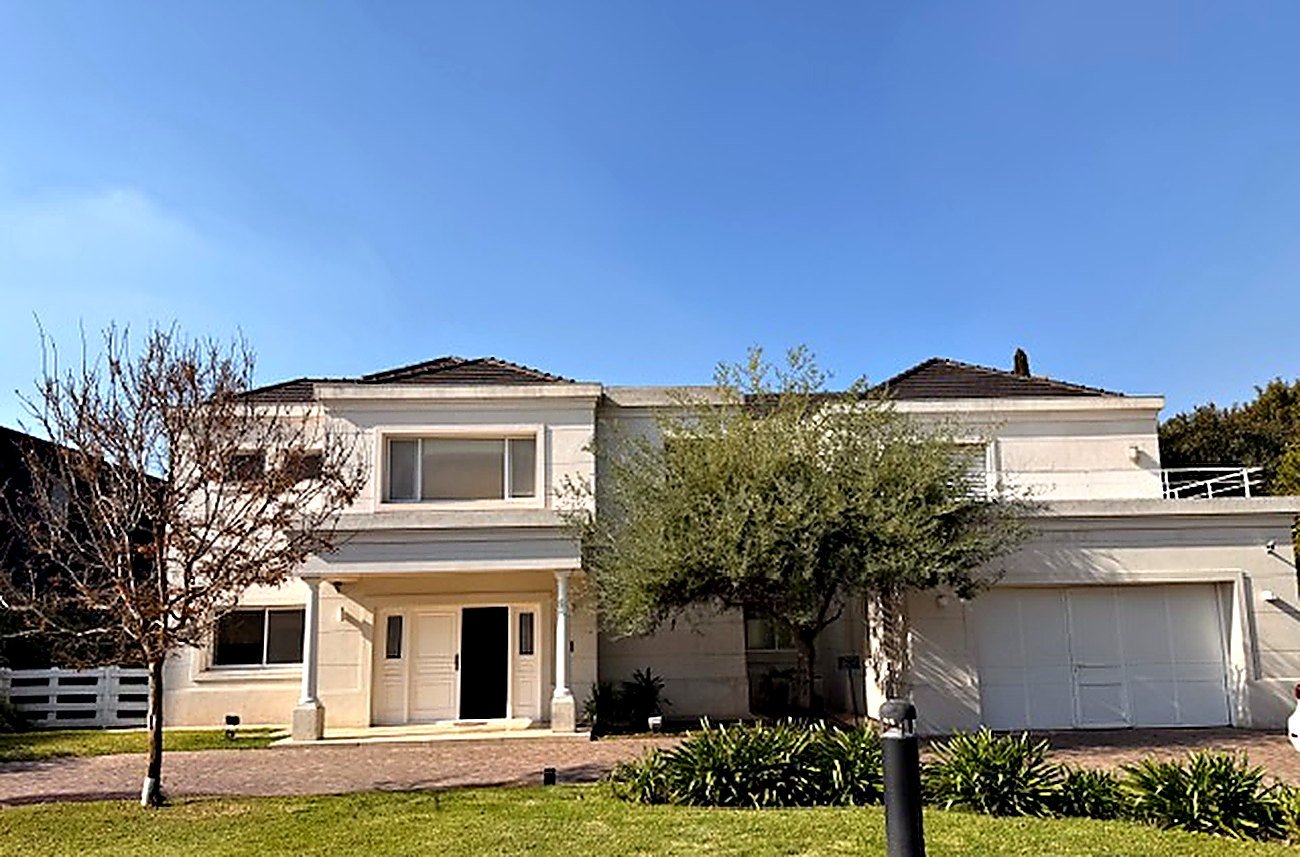 Full front view of the white villa with double garage in a gated golf community near Rosario, Argentina