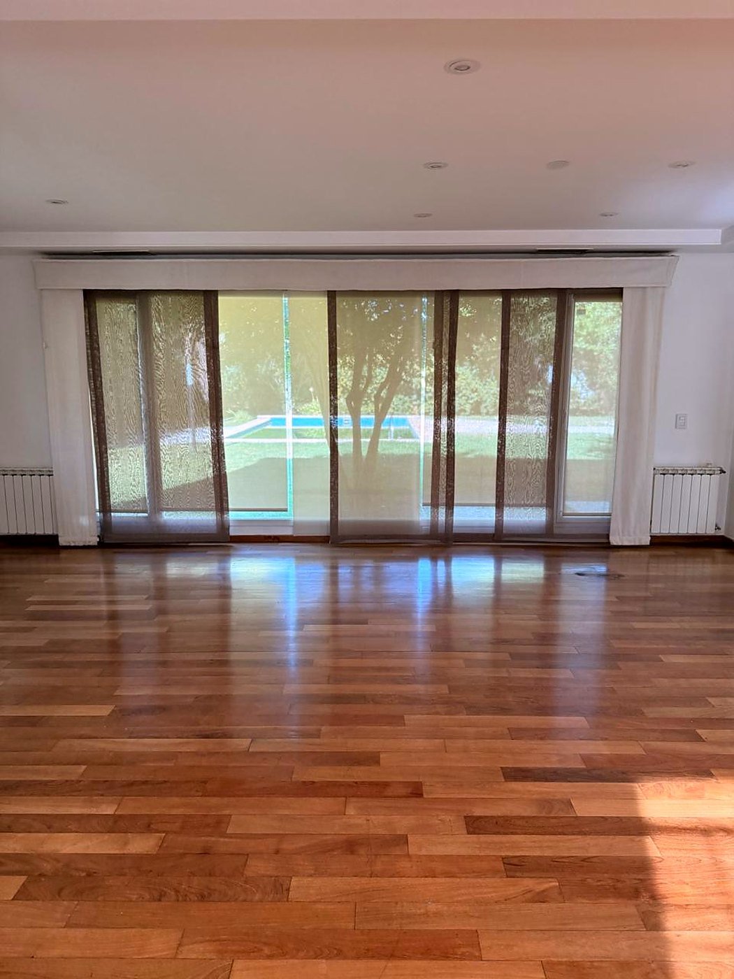 Living room with a wall of sliding glass looking out to the lawn and swimming pool