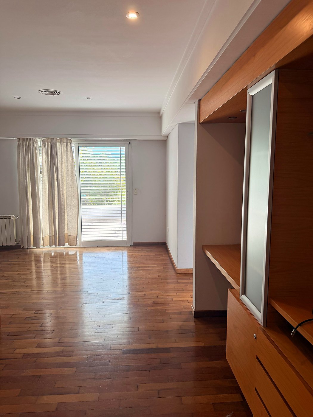Family room with a fitted wood wall unit and sliding doors to a private balcony, Funes, Greater Rosario