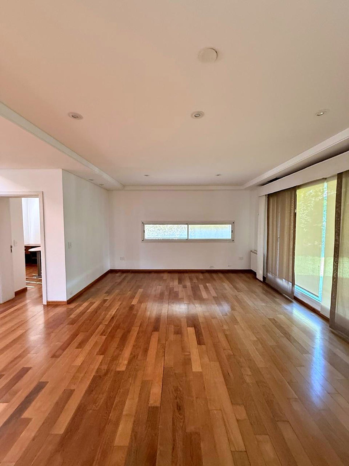 Reception room with wide plank floors and full-height glass to the garden